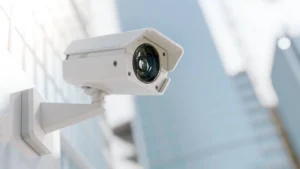 A white outdoor security camera mounted on a wall, representing weather-resistant home security monitoring for cold weather, winter, snow, and outdoor conditions.