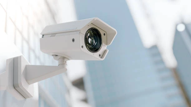 A white outdoor security camera mounted on a wall, representing weather-resistant home security monitoring for cold weather, winter, snow, and outdoor conditions.